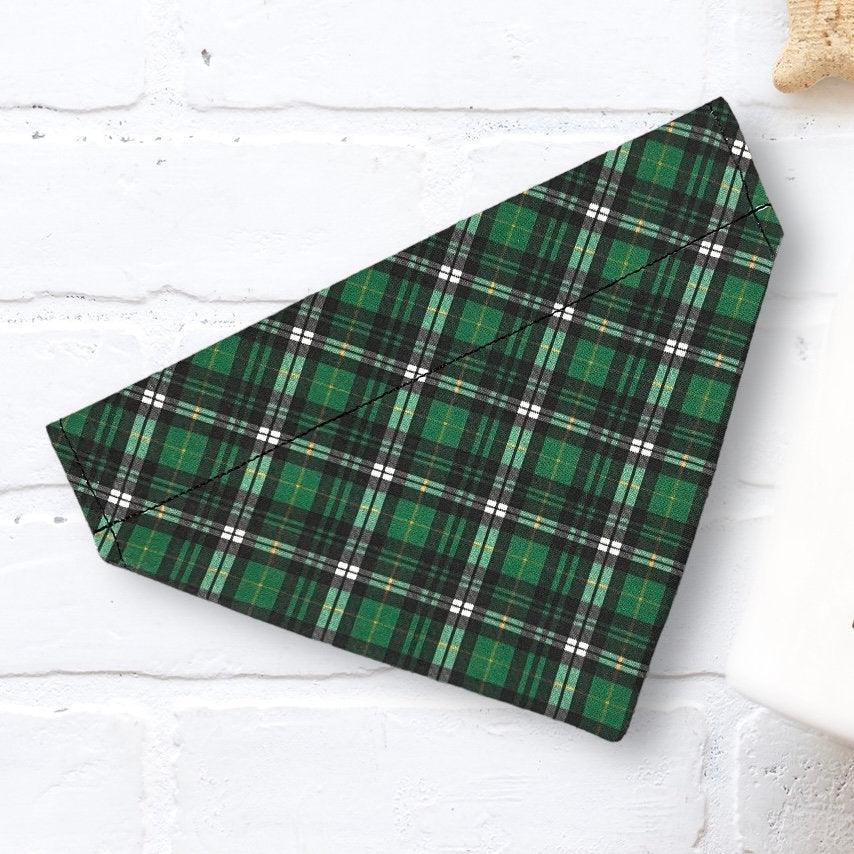 Green plaid Christmas dog bandana on a white wooden surface