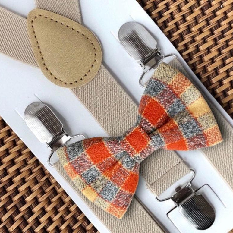 A set of fall-colored flannel bow ties and tan suspenders, displayed on a cardboard backing, with fasteners attached to the top of the bow ties.