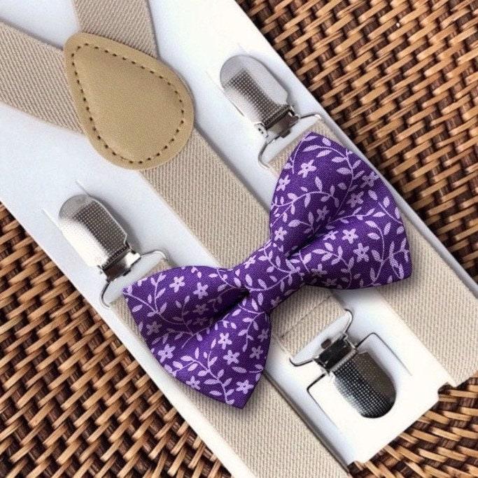 Purple floral bow tie with beige suspenders on a woven surface