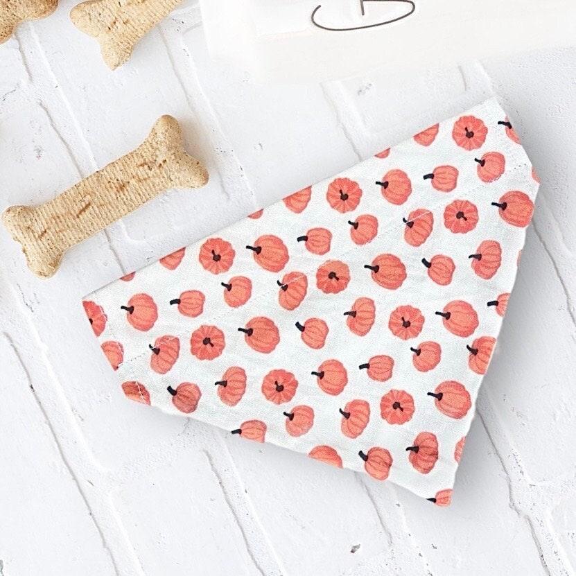 Folded white fabric bandana with orange pumpkin pattern for dogs and cats.