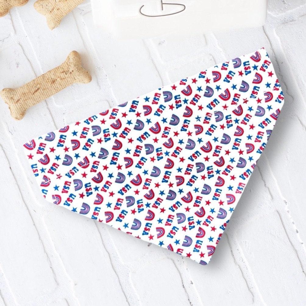 Flat lay of a patriotic rainbow dog bandana on a white textured surface with bone shapes around it