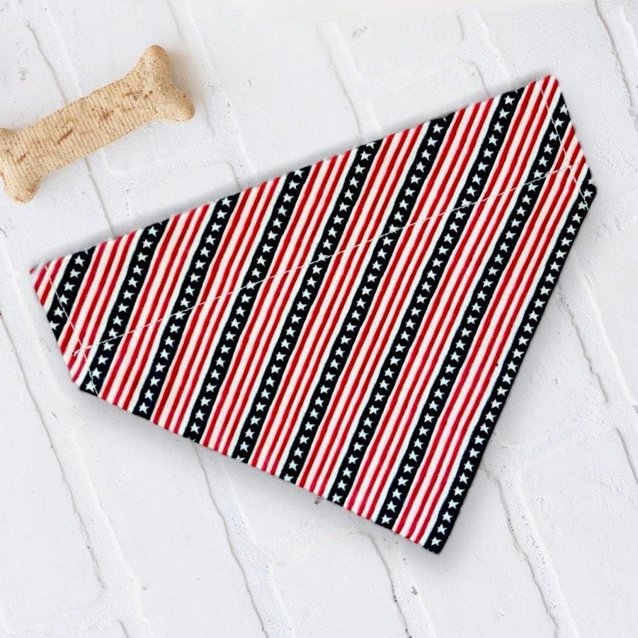 Patriotic red white and blue striped dog bandana laid on a white textured surface