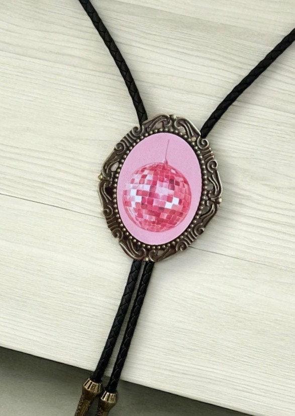 Pink disco ball pendant in a bronze ornate frame with a black braided bolo cord close up