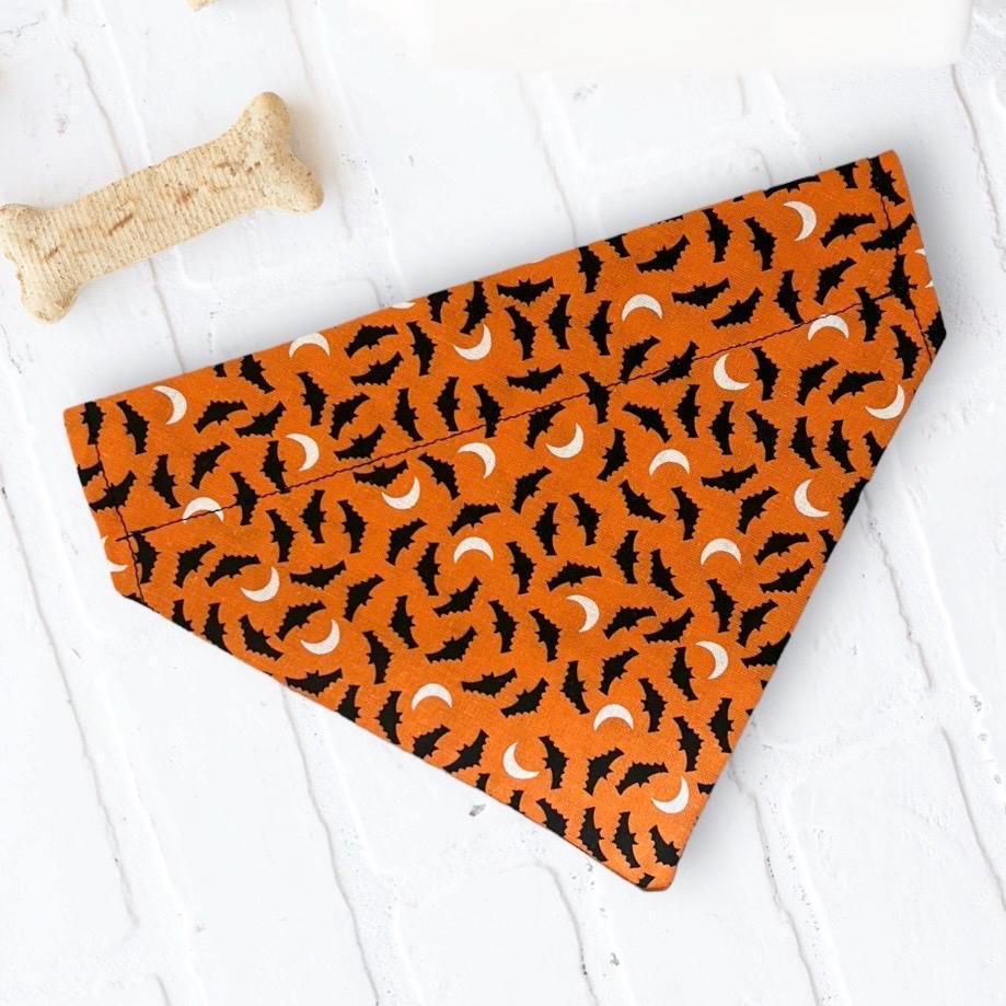 Orange pet bandana with black bat silhouettes arranged in a Halloween pattern