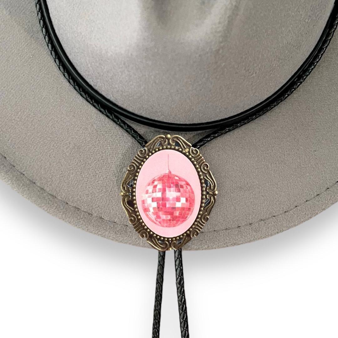 Pink disco ball pendant on an ornate bronze bezel with a black braided bolo cord