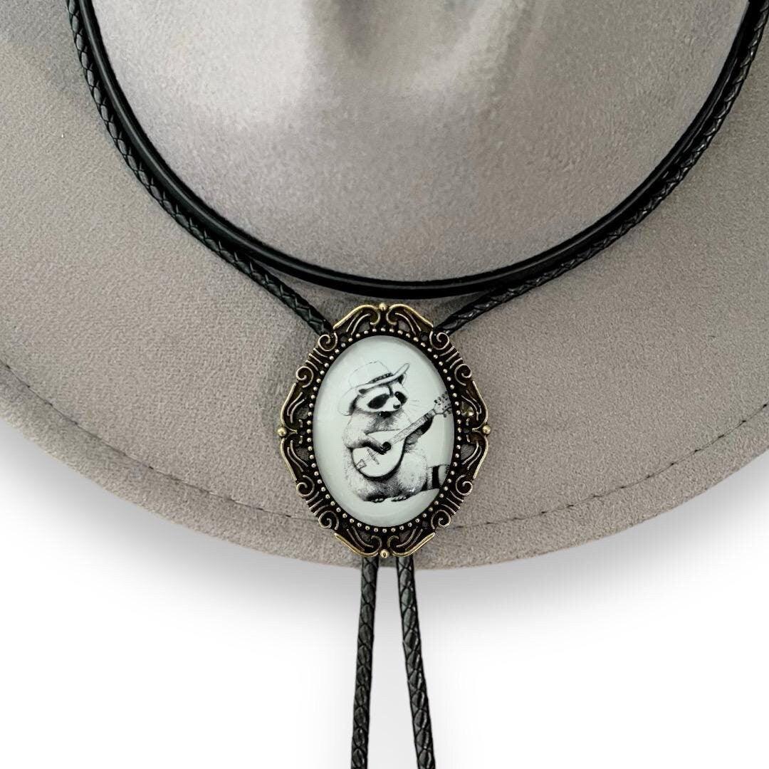 Raccoon bolo tie in black white and bronze hanging from a gray cowboy hat.