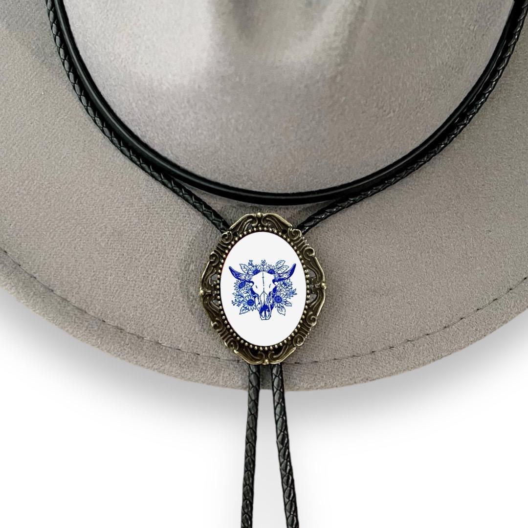 Bolo tie size chart from The Bold Bow Tie. The image displays a braided leather bolo tie with a round silver concho-style slide and silver metal tips, set against a multi-colored striped fabric background. A vertical dotted arrow on the right spans the full length of the piece, accompanied by text indicating a 39 inch cord length.