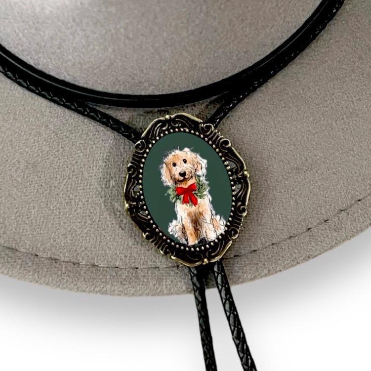 Ornate oval pendant bolo tie with a fluffy light brown dog wearing a red bow on black braided cords