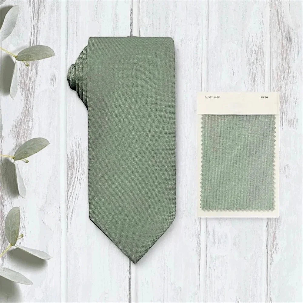 Sage green tie for men on a whitewashed wooden table.