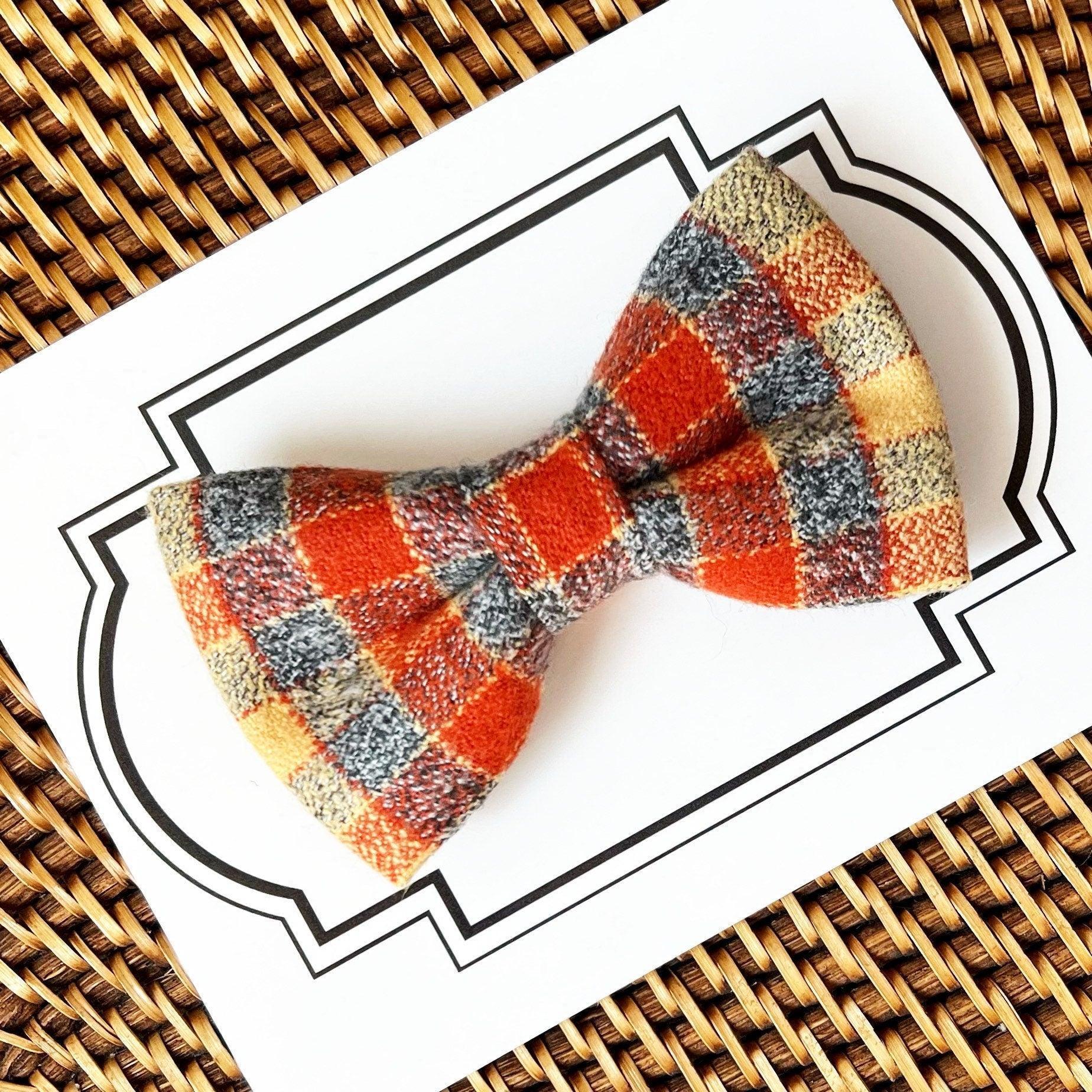 Size chart for pre-tied bow ties from The Bold Bow Tie detailing measurements across three sizes. Small is 3.5 inches wide and recommended for ages 6 months to 5 years. Medium is 4 inches wide and recommended for ages 6 to 12 years. Large is 4.5 inches wide and recommended for ages 13 years and up. Visual icons illustrate the relative sizes with horizontal arrows showing that width is measured from wingtip to wingtip. Bottom text notes that all bow ties are pre-tied and ready to add to your outfit.