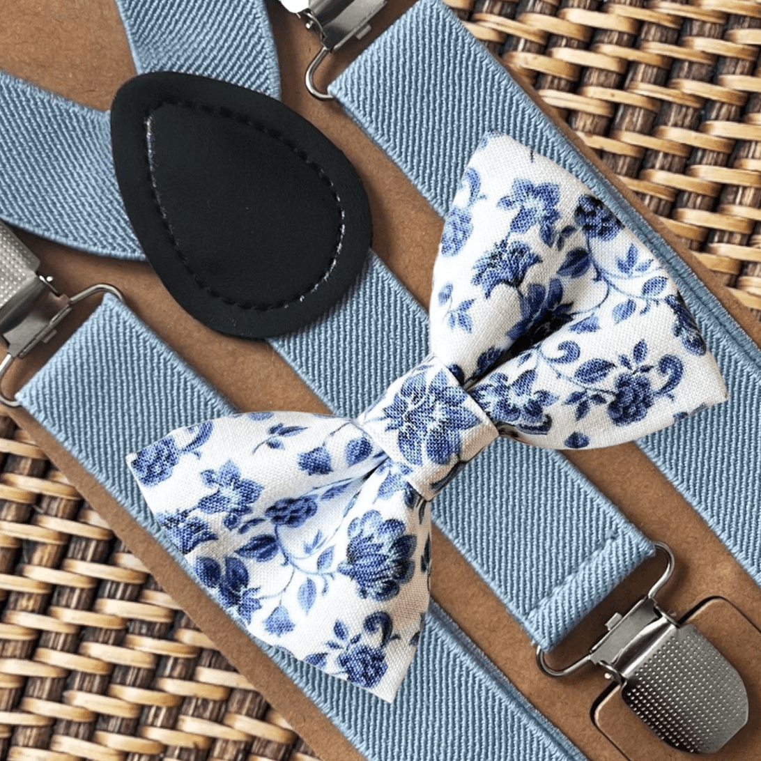 Dusty blue and white floral bow tie and dusty blue suspenders for a wedding, groomsmen, and ring bearer outfit.