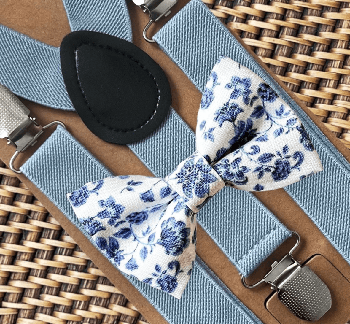 Dusty blue and white floral bow tie and dusty blue suspenders for a wedding, groomsmen, and ring bearer outfit.