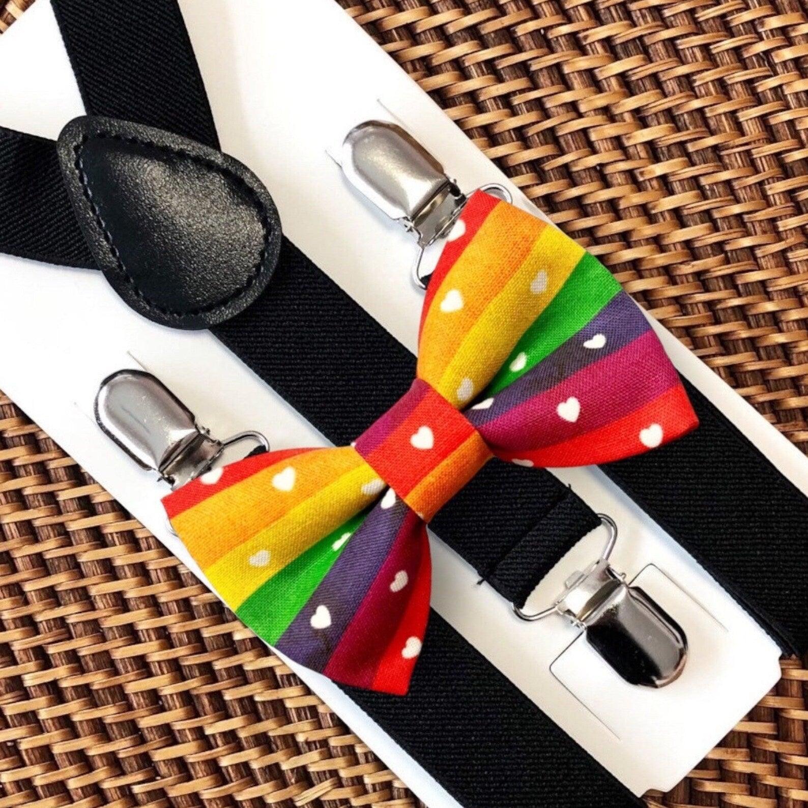 Rainbow bow tie with small white hearts with black suspenders on a woven surface for gay pride.