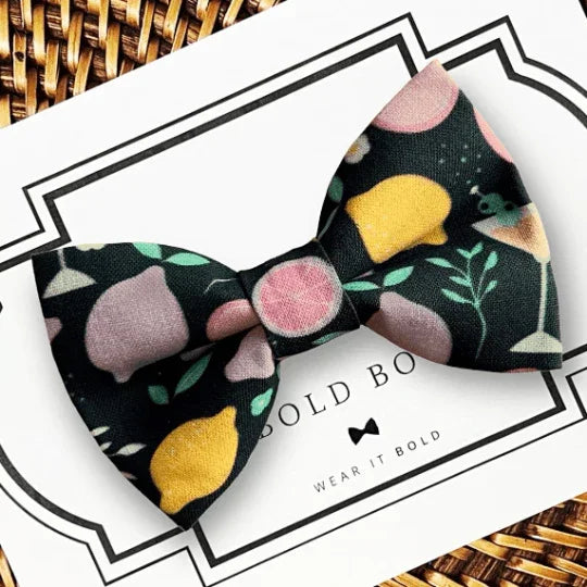 Citrus Cocktail bow tie with yellow pink citrus fruits on a black background, designed for dog or cat collars.