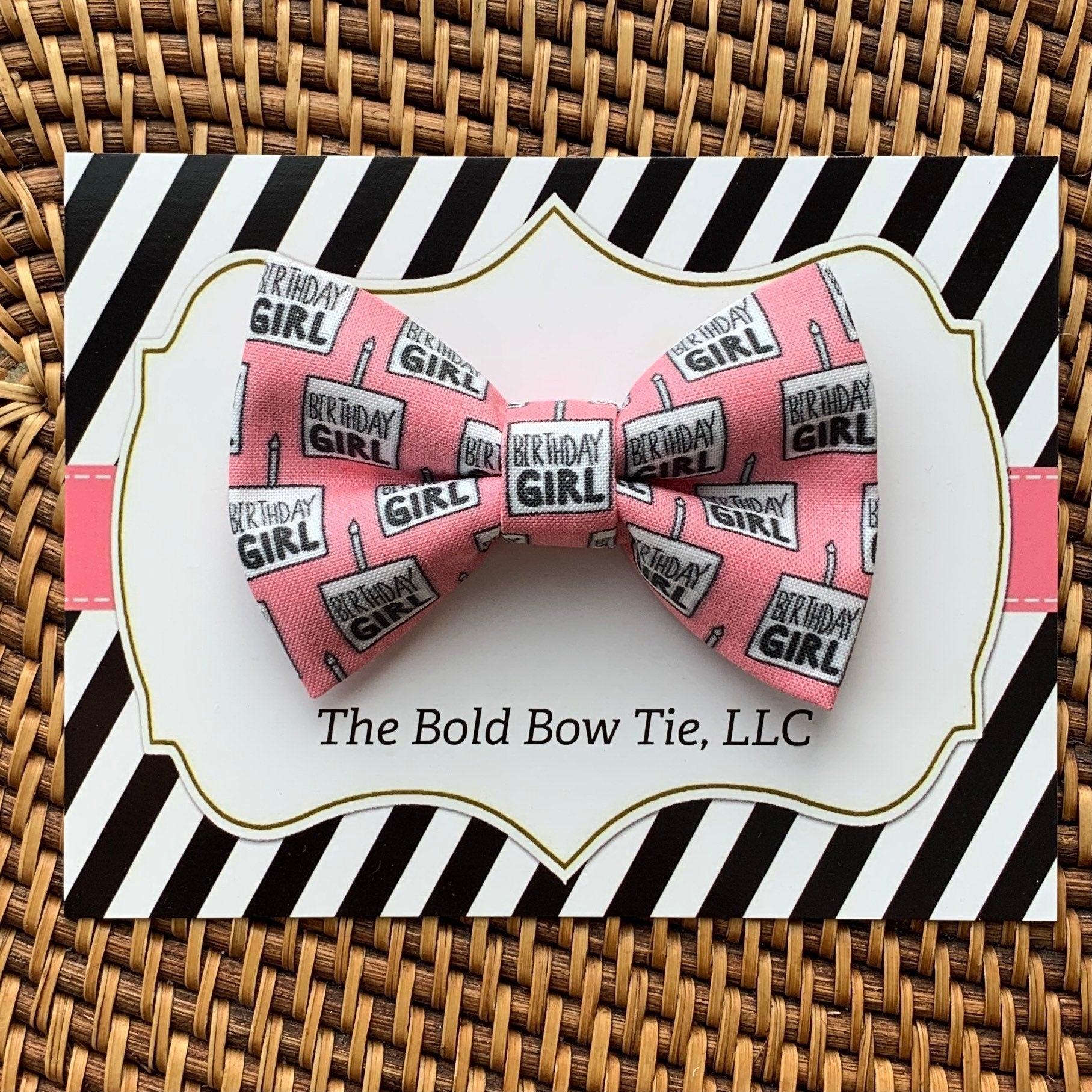 Pink Birthday Girl bow displayed on a striped decorative card inside a gift box