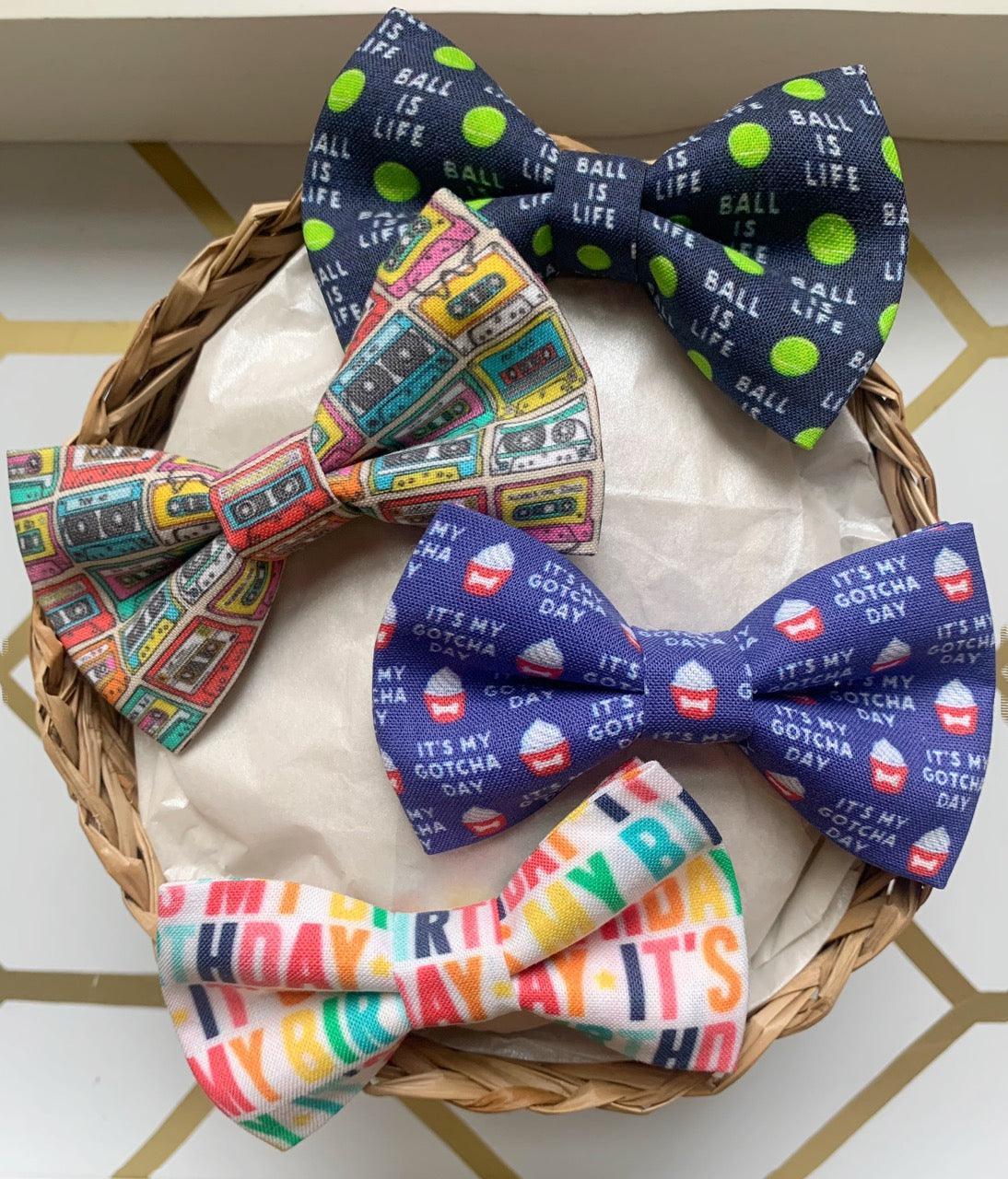 Basket with four colorful bow ties in playful patterns for pets including cassette tape and birthday text designs