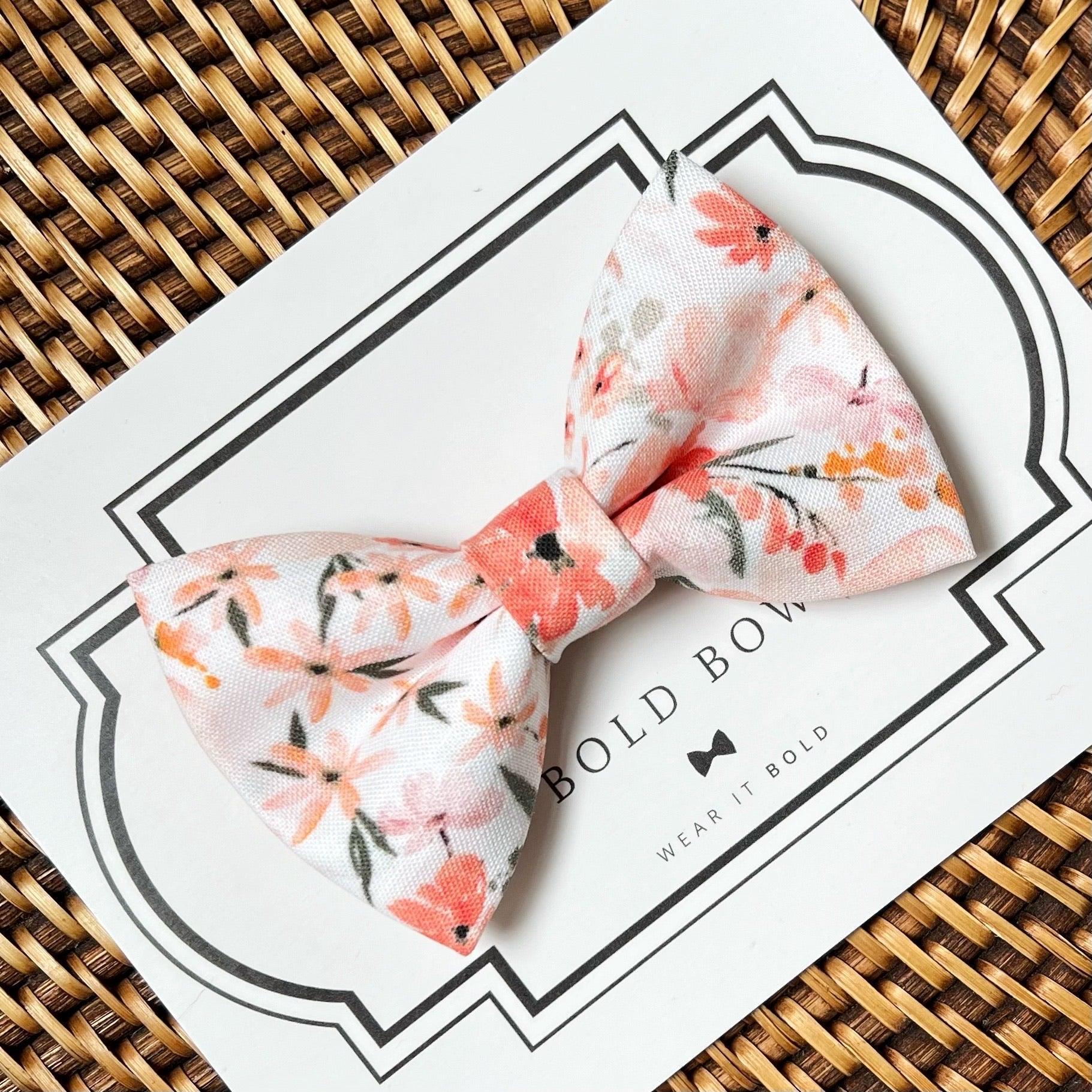 Size chart for pre-tied bow ties from The Bold Bow Tie detailing measurements across three sizes. Small is 3.5 inches wide and recommended for ages 6 months to 5 years. Medium is 4 inches wide and recommended for ages 6 to 12 years. Large is 4.5 inches wide and recommended for ages 13 years and up. Visual icons illustrate the relative sizes with horizontal arrows showing that width is measured from wingtip to wingtip. Bottom text notes that all bow ties are pre-tied and ready to add to your outfit.