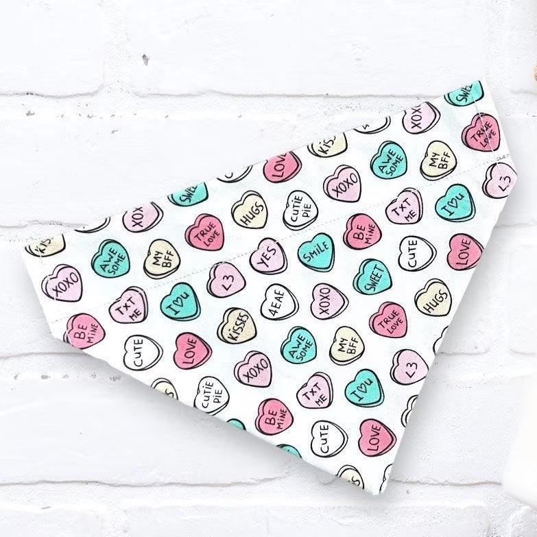 a dog bandana on a white wall with a bunch of hearts on it