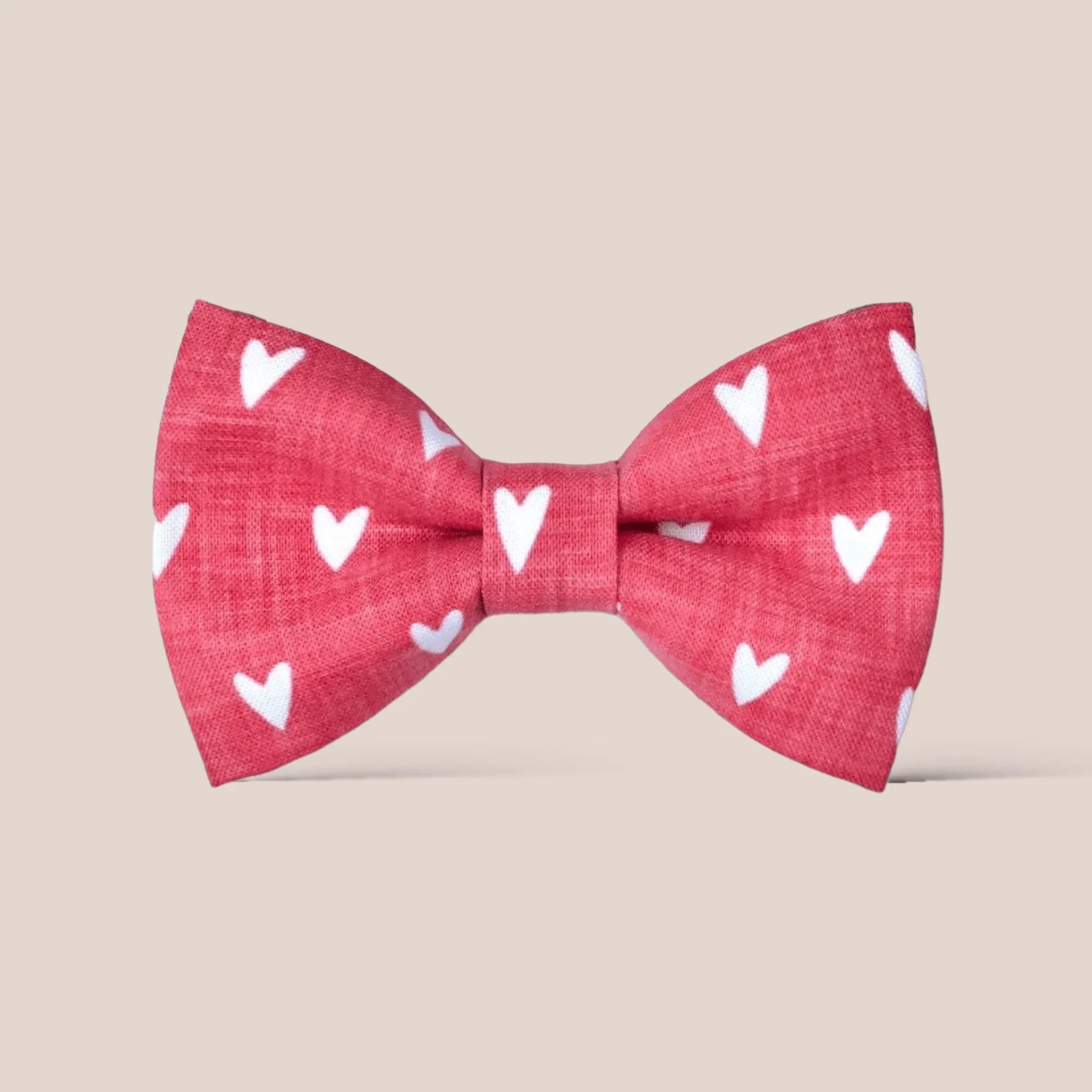 Red Valentines Day hair bow with white heart patterns on a beige background