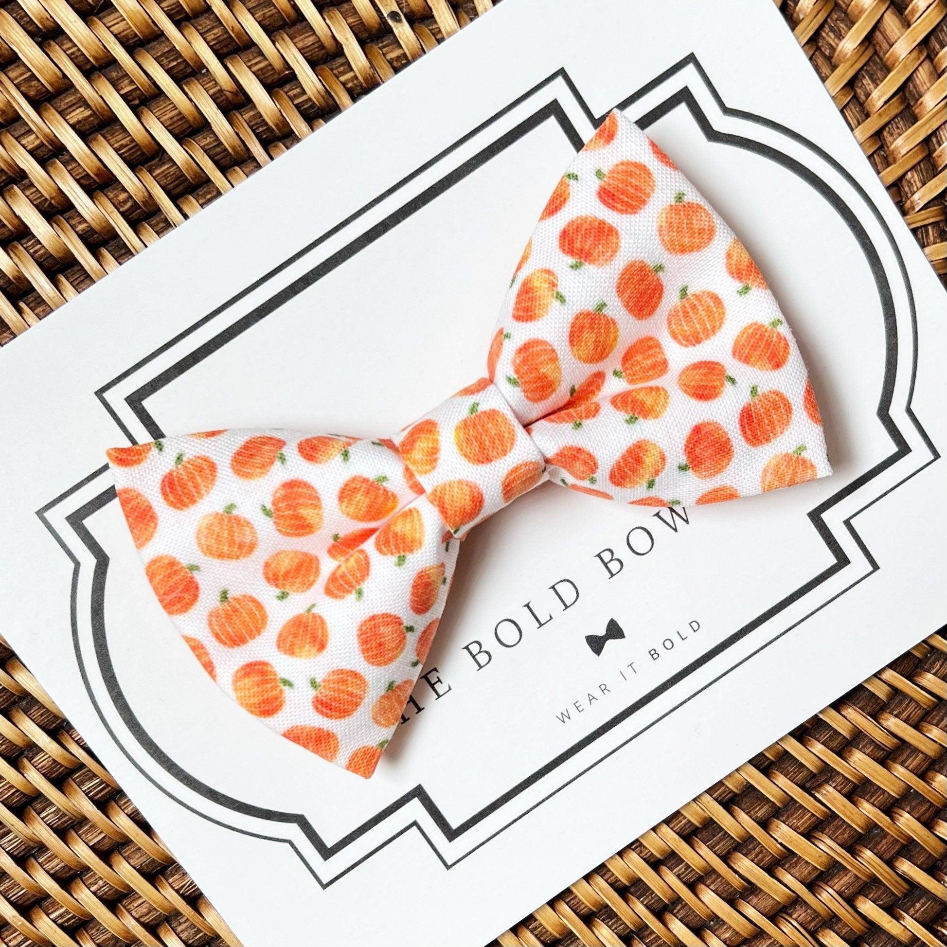 Size chart for pre-tied bow ties from The Bold Bow Tie detailing measurements across three sizes. Small is 3.5 inches wide and recommended for ages 6 months to 5 years. Medium is 4 inches wide and recommended for ages 6 to 12 years. Large is 4.5 inches wide and recommended for ages 13 years and up. Visual icons illustrate the relative sizes with horizontal arrows showing that width is measured from wingtip to wingtip. Bottom text notes that all bow ties are pre-tied and ready to add to your outfit.