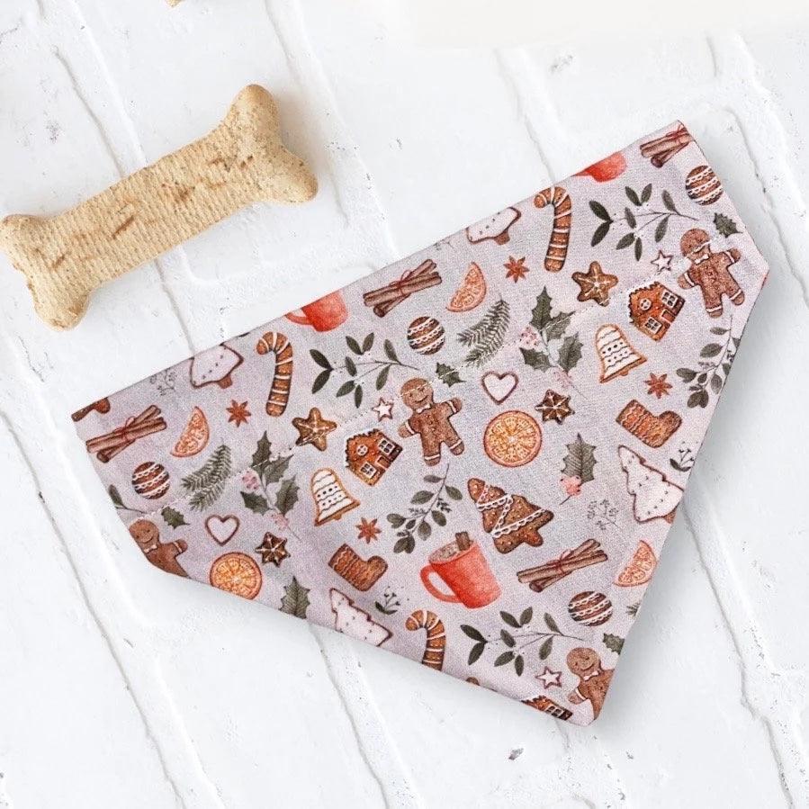 A Christmas dog bandana on a white table with a bone