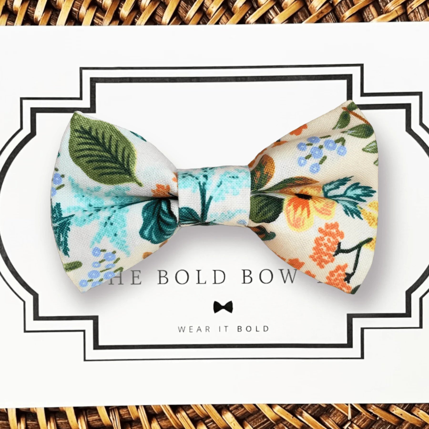 Blue floral bow tie on white packaging with a bold framed border