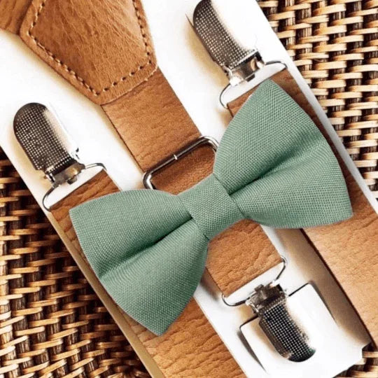 Green bow tie with brown suspenders on a woven surface