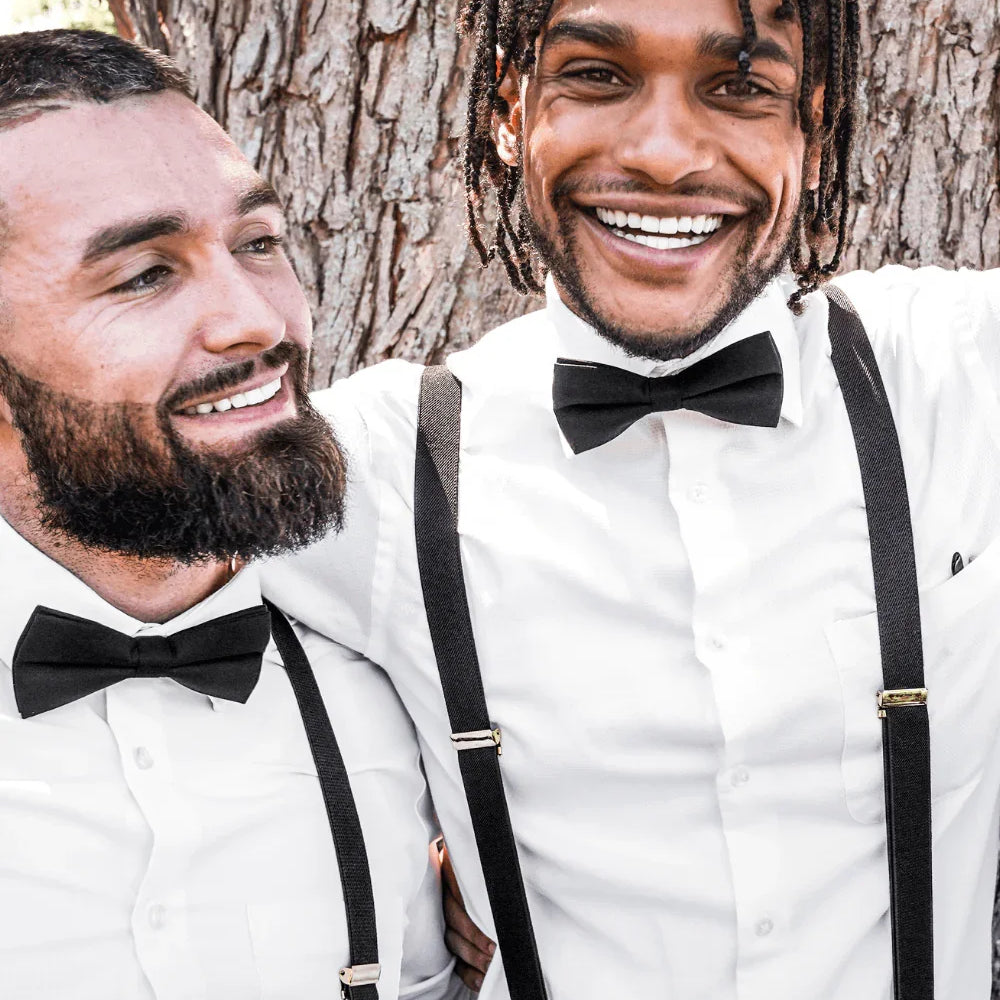 Groomsmen wearing black bow ties for men and black suspenders with silver clips.