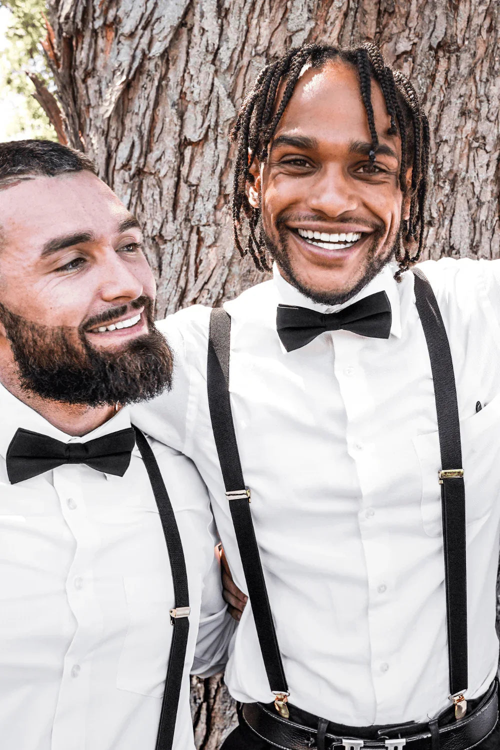 Groomsmen wearing black bow ties for men and black suspenders with silver clips.