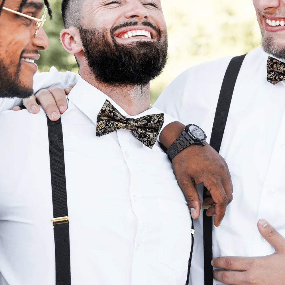 Groomsmen at a wedding wearing black and gold bow ties and black suspenders with gold clips.