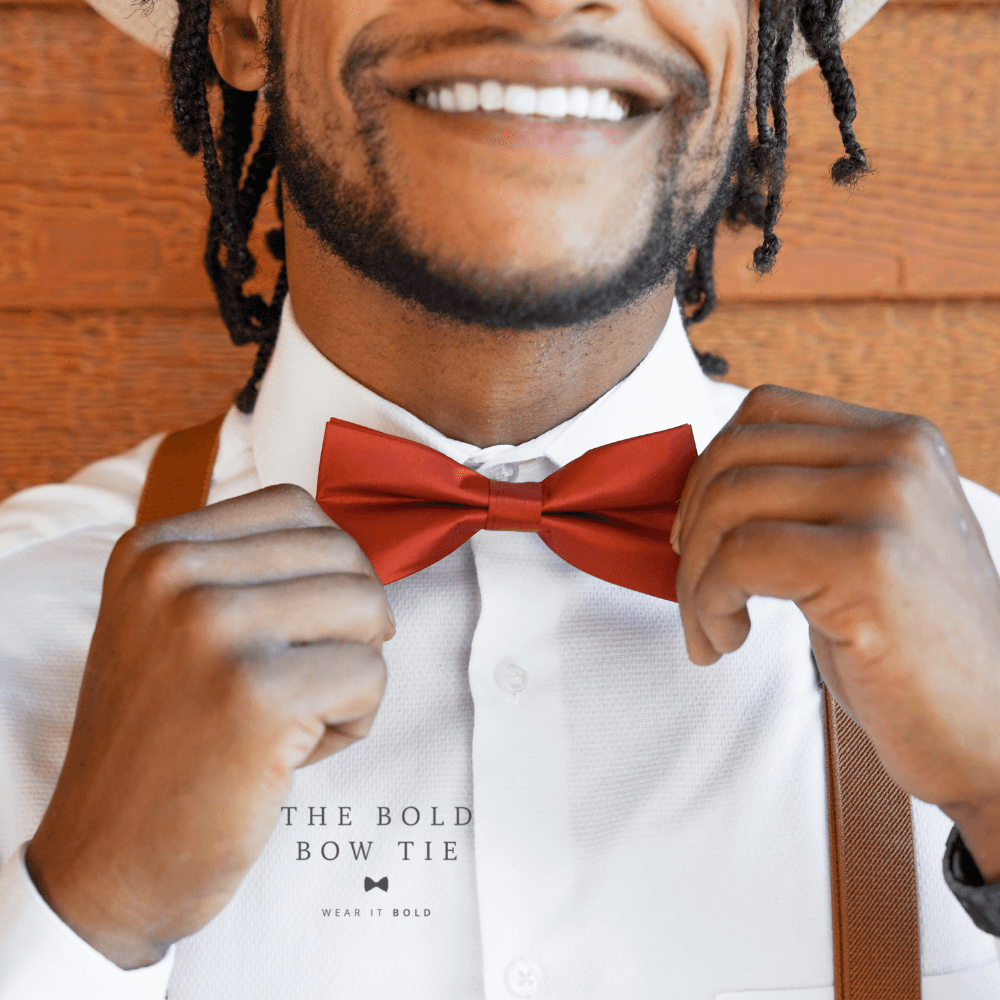 Groomsman in a burnt orange bow tie and suspenders.