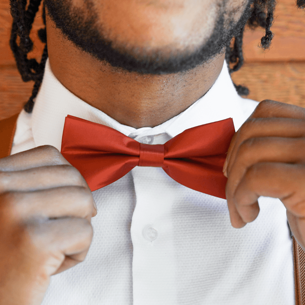 Groomsman in burnt orange rust bow tie and suspenders.