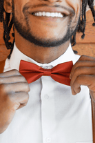 Groomsman in burnt orange rust bow tie and suspenders.