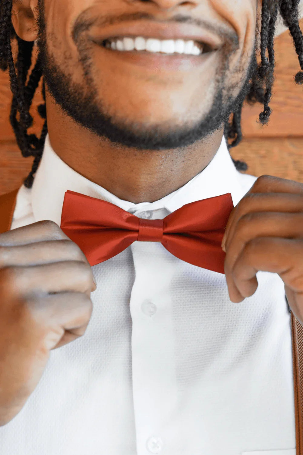 Groomsman in burnt orange rust bow tie and suspenders.