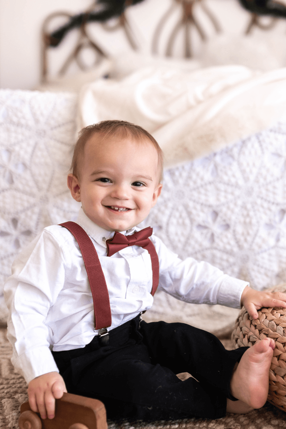 Ring bearer in cinnamon bow tie and suspenders getting ready to walk down the aisle at a wedding.
