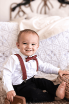 Ring bearer in cinnamon bow tie and suspenders getting ready to walk down the aisle at a wedding.