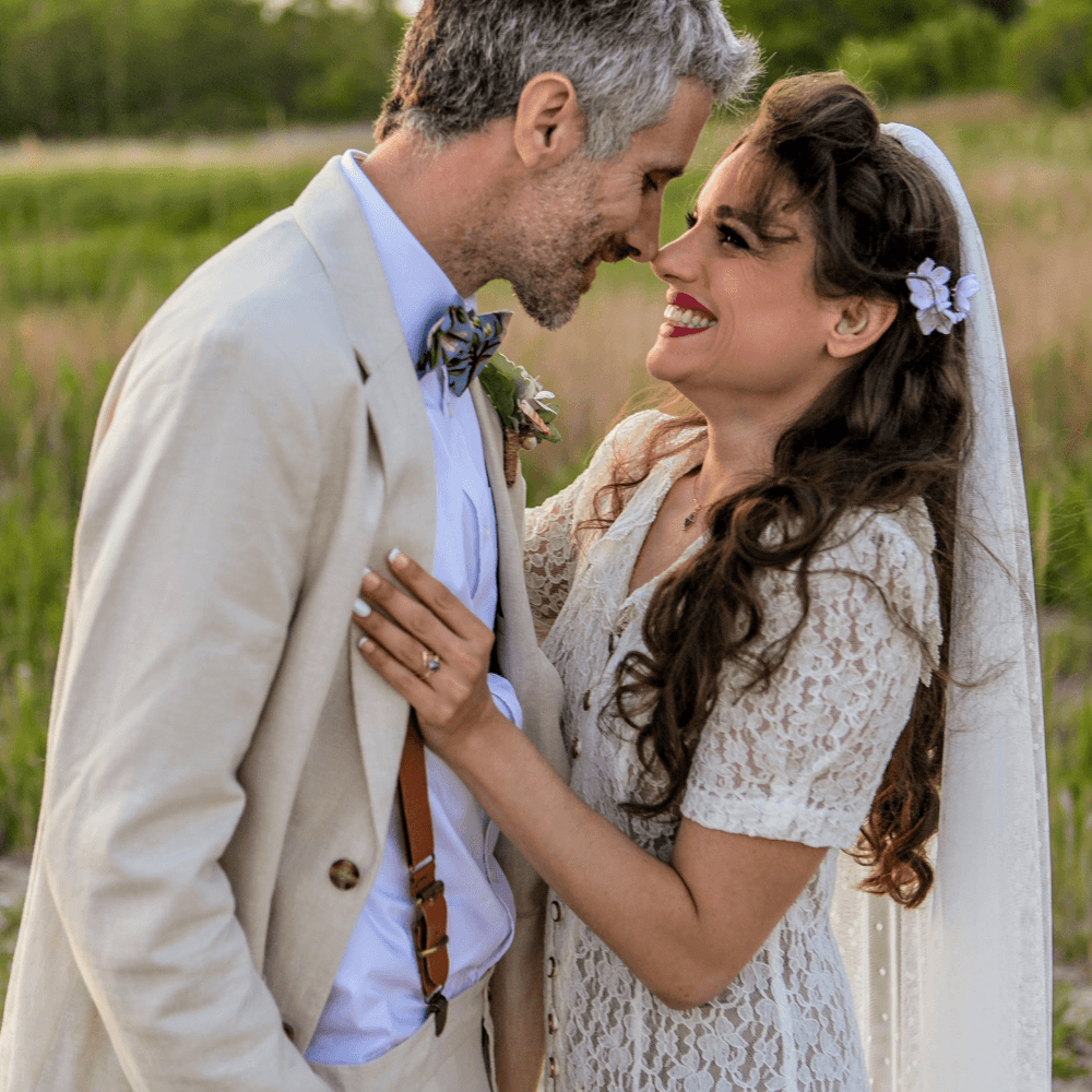 Dusty blue hydrangea bow tie worn by the groom in a wedding smiling with his bride.