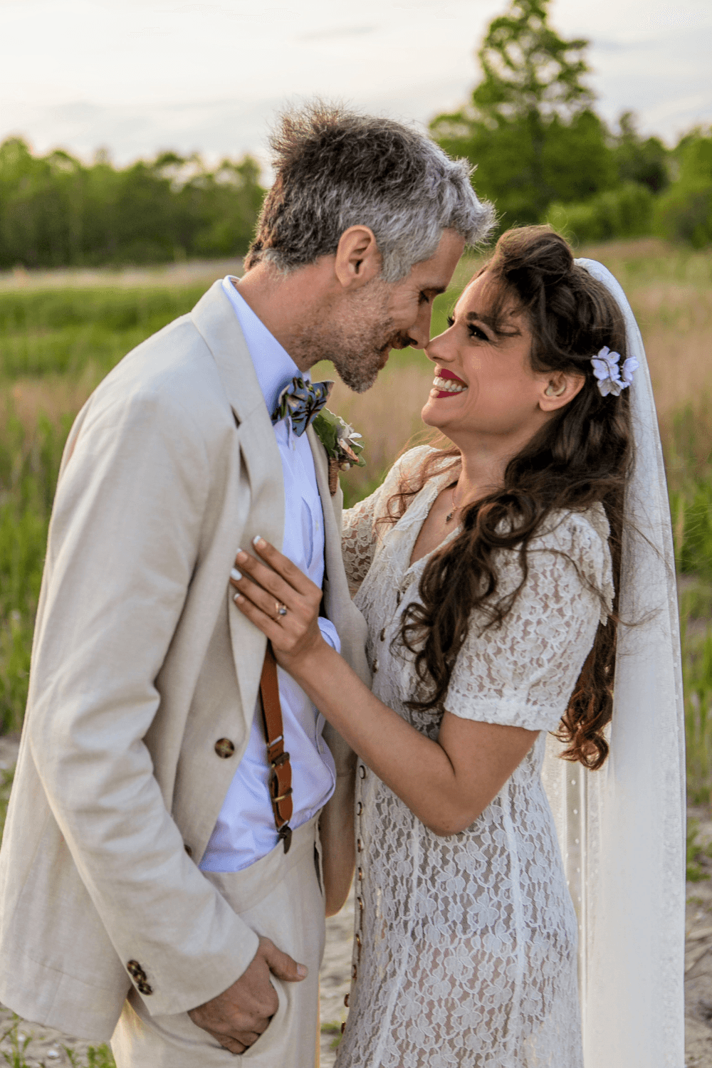Dusty blue hydrangea bow tie worn by the groom in a wedding smiling with his bride.