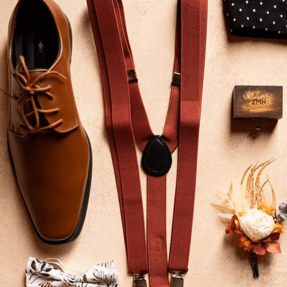 Groomsmen accessories with burnt orange suspenders and floral bow tie.