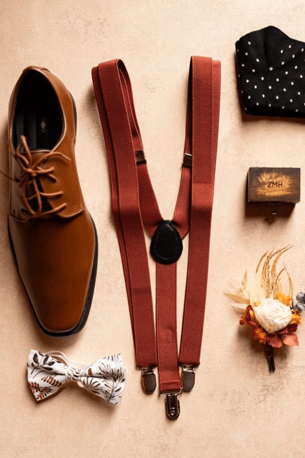 Groomsmen accessories with burnt orange suspenders and floral bow tie.