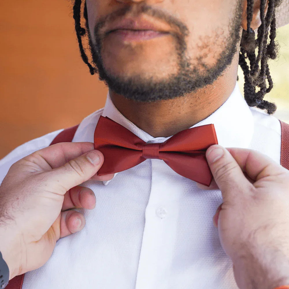 Size chart for pre-tied bow ties from The Bold Bow Tie detailing measurements across three sizes. Small is 3.5 inches wide and recommended for ages 6 months to 5 years. Medium is 4 inches wide and recommended for ages 6 to 12 years. Large is 4.5 inches wide and recommended for ages 13 years and up. Visual icons illustrate the relative sizes with horizontal arrows showing that width is measured from wingtip to wingtip. Bottom text notes that all bow ties are pre-tied and ready to add to your outfit.