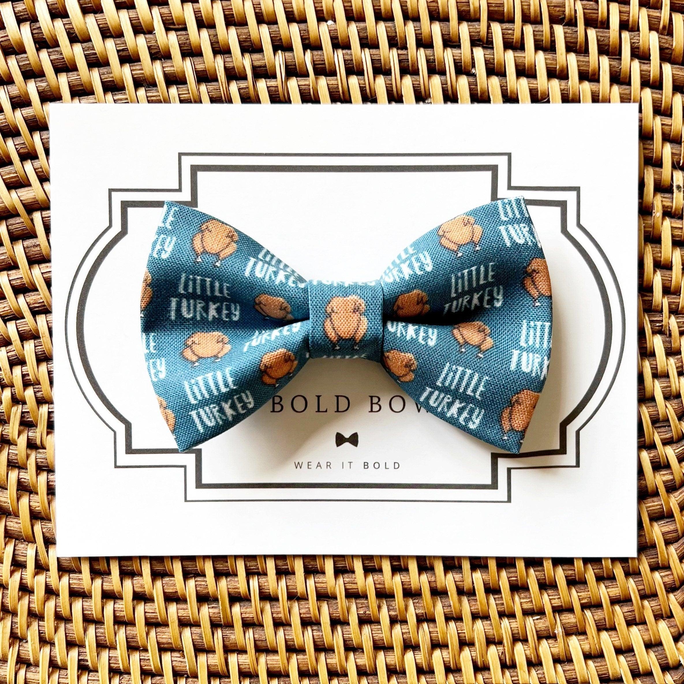 Blue Thanksgiving bow tie with orange turkey pattern displayed on a white gift card with decorative black frame