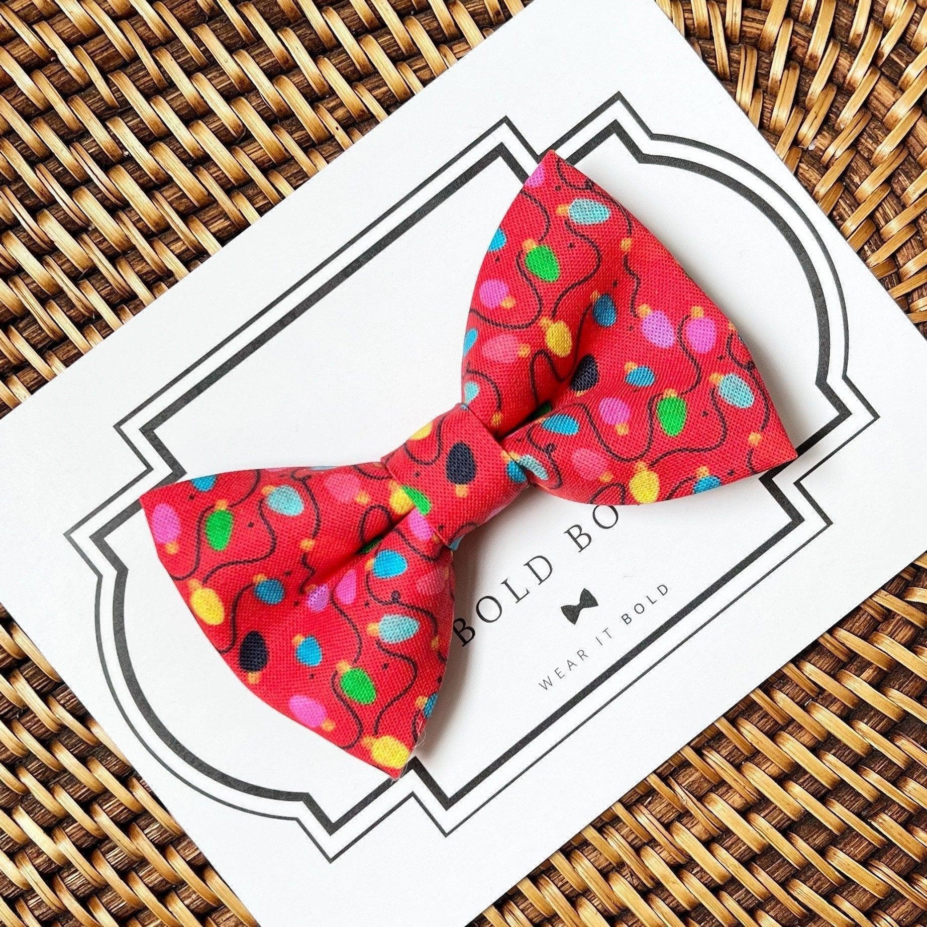 Size chart for pre-tied bow ties from The Bold Bow Tie detailing measurements across three sizes. Small is 3.5 inches wide and recommended for ages 6 months to 5 years. Medium is 4 inches wide and recommended for ages 6 to 12 years. Large is 4.5 inches wide and recommended for ages 13 years and up. Visual icons illustrate the relative sizes with horizontal arrows showing that width is measured from wingtip to wingtip. Bottom text notes that all bow ties are pre-tied and ready to add to your outfit.