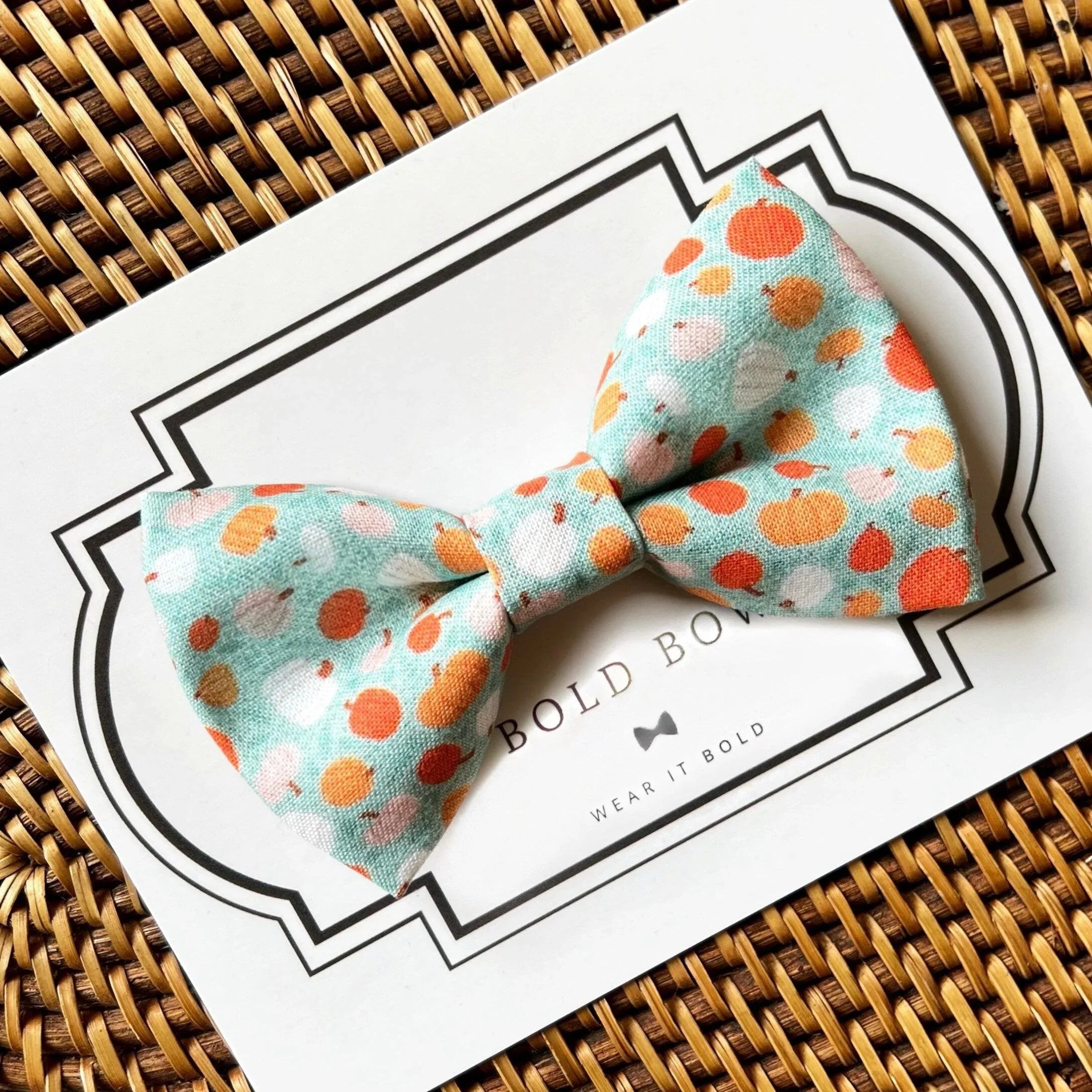 Size chart for pre-tied bow ties from The Bold Bow Tie detailing measurements across three sizes. Small is 3.5 inches wide and recommended for ages 6 months to 5 years. Medium is 4 inches wide and recommended for ages 6 to 12 years. Large is 4.5 inches wide and recommended for ages 13 years and up. Visual icons illustrate the relative sizes with horizontal arrows showing that width is measured from wingtip to wingtip. Bottom text notes that all bow ties are pre-tied and ready to add to your outfit.