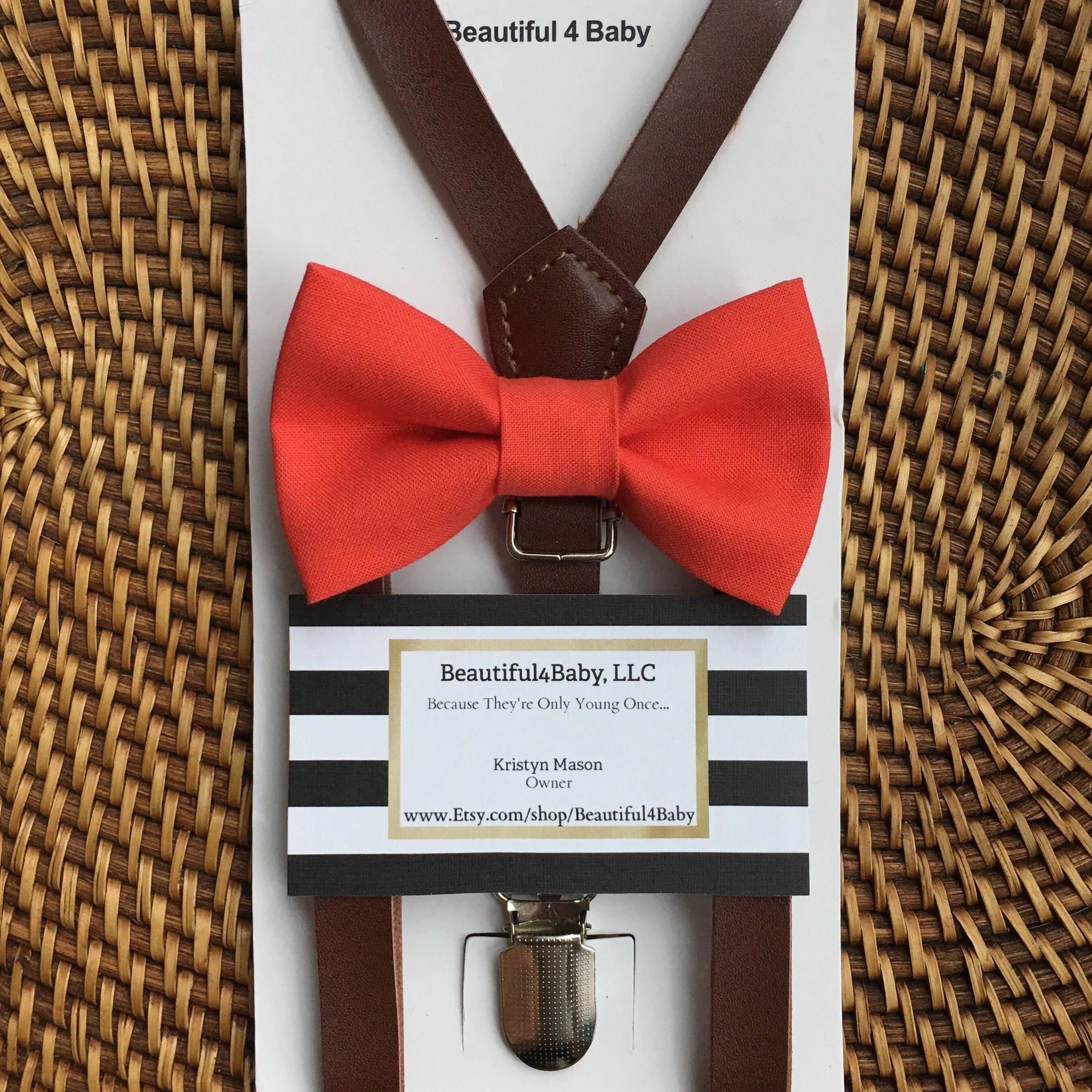 Coral bow tie and brown suspenders for a wedding on a woven background.