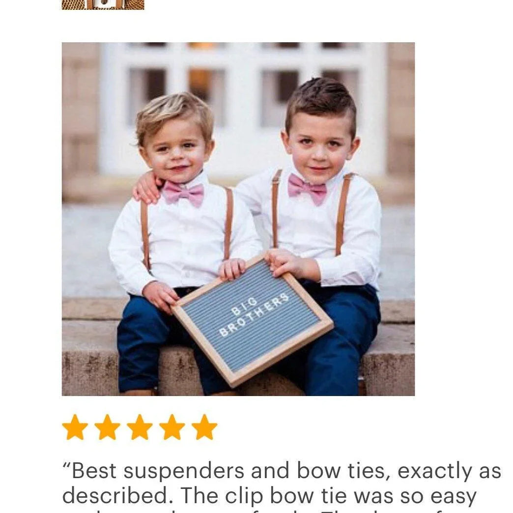 Two elementary school boys in dusty rose bow ties for boys and brown suspenders for a wedding with a "Big Brothers" sign.