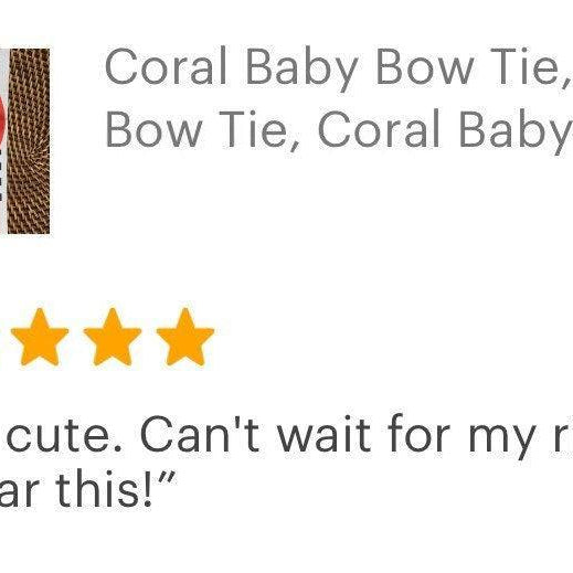 Coral baby bow tie with dark brown vegan leather suspenders on a display with a product tag.