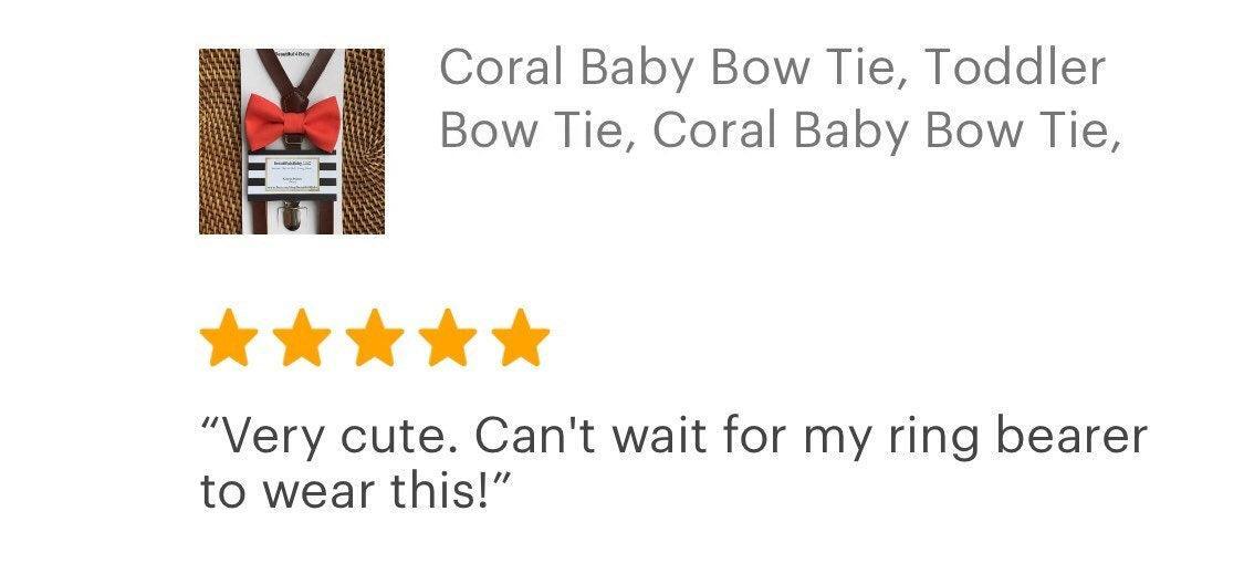 Coral baby bow tie with dark brown vegan leather suspenders on a display with a product tag.