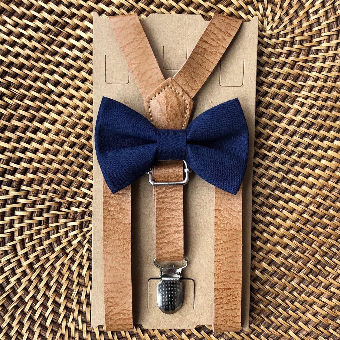 Close-up of navy bow tie and tan suspenders secured to a cardboard backing
