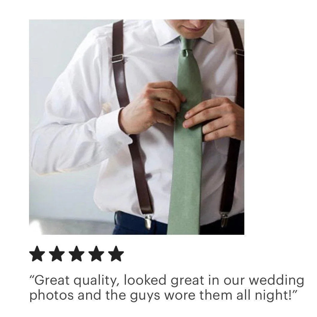 Man in a white shirt wearing dark brown leather suspenders with a green tie, adjusting the tie
